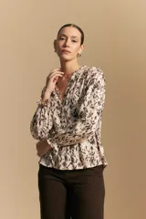 Camisa de manga larga con silueta relajada, estampado a rayas verticales en blanco y gris, escote abierto con botones frontales y puños elastizados.