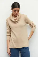 Polera de cuello alto holgado, manga larga y diseño de tejido fino con aberturas laterales en el ruedo.