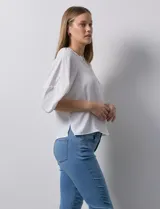 Blusa de gasa blanca con estampado de hojas en azul marino, cuello a la base con escote en V y botones, y mangas cortas abullonadas.