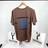 Remera marrón de mangas cortas con estampa en la espalda que incluye una flor azul, la frase "Boundless Art" y números.