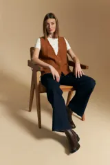 Chaleco tejido color azul, con escote en V, cierre frontal con botones y diseño de líneas verticales en relieve. Presenta terminaciones acanaladas en el ruedo y un borde ondulado en el escote.