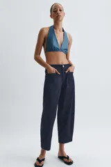 Pantalón de jean azul oscuro de tiro medio, con corte holgado y diseño de pierna ancha. Presenta cintura elástica en la parte posterior, cierre frontal con cremallera y botón metálico, y bolsillos de plastrón en el delantero.