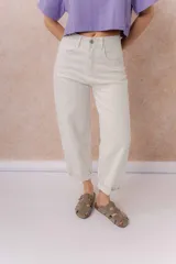 Jeans de tiro alto y silueta barrel, color crudo, con cinco bolsillos, presillas para cinturón y cierre frontal con botón y cremallera. Presenta diseño de pierna amplia con leve entalle hacia el ruedo y dobladillo vuelto.