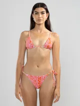 Conjunto de bikini de dos piezas con estampado abstracto en tonos rosados y naranjas. El corpiño es de corte triangular con tirantes finos regulables y se ata en la espalda. La bombacha es de corte triángulo con lazos ajustables a los laterales.