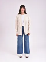 Cardigan abierto de punto color beige con bolsillos frontales y detalles de tejido acanalado en los hombros.