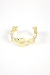 Brazalete rígido dorado con diseño de flores.