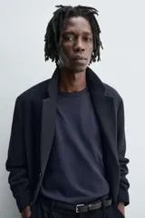 Abrigo de corte regular fit confeccionado en tejido compacto con mezcla de lana. Presenta cuello con solapas de muesca, cierre frontal de botonadura, bolsillos de vivo en la cadera y abertura central en la espalda.