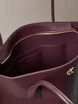 Cartera tote Calvin Klein de color marrón oscuro, con doble asa de hombro, cierre de cremallera superior y monograma metálico dorado en la parte frontal.