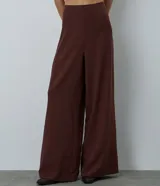 Pantalón de sastrería modelo pantalona, de corte amplio y tiro alto, con cintura lisa y pliegues frontales. Confeccionado en tejido de poliéster con elastano.