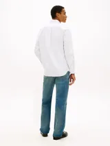 Camisa blanca de manga larga en tejido Oxford, de corte regular, con cuello abotonado y cierre frontal de botones. Cuenta con un pequeño logo bordado en el pecho.