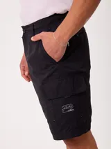 Bermuda cargo lisa de color negro, con múltiples bolsillos laterales, trabillas para cinturón y cierre frontal con botón y cremallera.