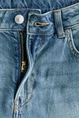 Jean de tiro alto y corte baggy, confeccionado en denim de algodón rígido en color celeste con efecto deslavado. Presenta diseño de cinco bolsillos, piernas rectas y holgadas, y cierre frontal con botón y cremallera.