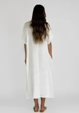 Vestido midi de lino en color beige, con diseño holgado, cuello redondo y detalles de costuras con terminaciones desflecadas en el frente y las mangas.