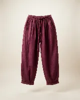 Pantalón de lino color bordó, de silueta relajada y amplia, con cintura elastizada, lazo de ajuste y detalle de pequeños pliegues y ruedo desflecado.