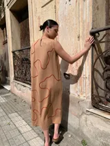 Vestido midi sin mangas color beige con estampado de líneas onduladas color ladrillo.