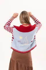 Saco tejido de punto a rayas horizontales en color celeste y rojo, con cuello alto, cierre frontal doble deslizador y puños con diseño en contraste. Presenta un pequeño bordado en el pecho.