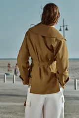 Chaqueta estilo trench corta color azul marino confeccionada con lino. Cuenta con cuello solapa, manga larga con trabilla, bolsillos delanteros de vivo y cierre frontal con lazada ajustable en la cintura.