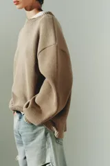 Jersey de punto liso con diseño oversize, cuello redondo y manga larga con puños acanalados.