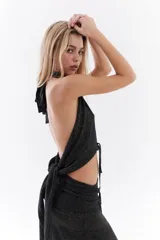 Top halter color bordó con tejido de lurex, escote con tiras cruzadas en el cuello y abertura frontal pronunciada con cordones ajustables.