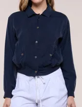 Camperita bomber de lyocell con textura suave, color azul marino, cuello camisero, cierre frontal con botones a presión, bolsillos laterales con solapa, mangas largas con puños elásticos y pretina fruncida en el ruedo.