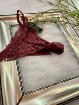 Pack de tres tangas de encaje con diseño floral, breteles regulables y laterales finos. El conjunto incluye una tanga rosa claro, una tanga color tostado con bordes grises y una tanga roja.