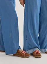 Championes marrones de cuero con cordones intercambiables blancos y rosas, y logo bordado en el lateral.