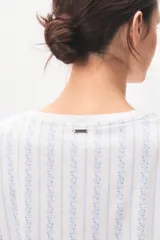 Pijama de algodón compuesto por una remera de manga corta con cuello redondo y un short con cordón ajustable en la cintura, ambos con diseño de rayas verticales formadas por pequeños motivos florales en tonos azules sobre fondo blanco.