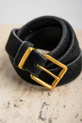 Cinto negro de gamuza con hebilla cuadrada dorada. Accesorio clásico y elegante para complementar cualquier outfit.