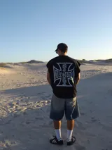 Musculosa negra con estampado de cruz de hierro con el texto "GUZE STUDIO" en letras góticas.