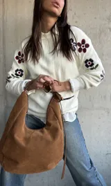 Sweater de punto color natural con cuello redondo y diseño de flores bordadas en las mangas. Presenta puños y ruedo acanalados.