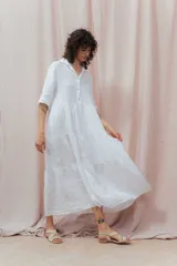 Vestido midi blanco de lino, con cuello camisero, botonera frontal y mangas 3/4. Presenta un calce relajado con frunces en la cintura.