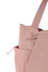 Cartera tipo tote bag de nylon color negro, con bolsillos laterales con cordón ajustable, asas de hombro y detalle de etiqueta frontal.