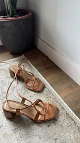 Sandalia de cuero color beige con tiras finas y taco de madera.