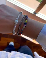 Pulsera elástica compuesta por cuentas de cristal transparente, con una cuenta central blanca decorada con strass y separadores brillantes.