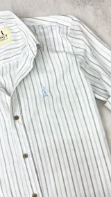 Camisa de algodón a rayas verticales celestes y grises claros, con cuello italiano y botones marrones.