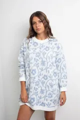 Vestido tejido de punto con diseño oversize, estampado floral en tonos celeste y blanco, cuello redondo y mangas largas con puños acanalados.