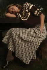 Jersey de punto color marrón con cuello redondo y manga corta abullonada. Presenta un diseño jacquard combinado en tonos beige, blanco y marrón en el canesú y los puños.