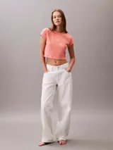 Remera cropped de Calvin Klein, color salmón, con cuello redondo, manga corta y logo de la marca bordado en el centro del pecho.