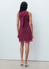 Vestido corto sin mangas con cuello alto y estampado geométrico en tonos rojo, violeta y marrón.