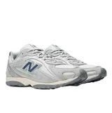 Championes New Balance modelo 204L, de estilo running inspirado en los años 2000. Presentan una combinación de colores gris y crema con detalles en azul marino, confeccionados con una capellada de gamuza premium y malla, con el logo N característico en los laterales y una entresuela liviana de EVA.
