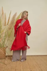 Ruana tejida color rojo, con terminación en flecos de lana y diseño en V en la espalda.