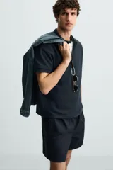 Polo de manga corta color blanco roto, con cuello solapa y cierre frontal de cremallera. Presenta un tejido de piqué estructurado y corte regular fit.