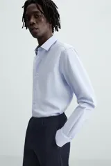 Camisa de corte regular fit en color celeste, con cuello italiano, manga larga con puños abotonados y cierre frontal de botones.