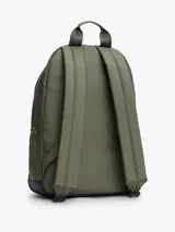 Mochila de diseño redondeado en color verde militar con base en azul marino. Cuenta con un compartimento principal con cierre de cremallera, un bolsillo frontal con cierre, asa superior y correas acolchadas ajustables. Incluye el parche distintivo de Tommy Jeans en la parte frontal.