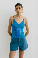 Musculosa elastizada color azul vibrante con escote en V y tirantes finos. Presenta un estampado frontal abstracto en tonos de azul y verde.