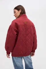 Campera bomber de gabardina con diseño capitoneado, cuello alto, cierre frontal con botones a presión ocultos y mangas abullonadas con puños elásticos.