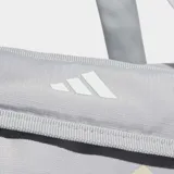 Bolso deportivo Adidas de color gris claro con logo estampado en tono beige. Cuenta con compartimento principal con cierre, bolsillo frontal con cremallera, correas de mano y correa de hombro ajustable con hombrera acolchada.