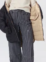 Campera reversible capitoneada con cierre frontal. Un lado es de color negro y el otro es de color beige, ambos con diseño acolchado. Cuenta con cuello redondo, mangas largas y bolsillos laterales.