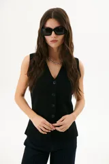 Chaleco tejido de punto en color beige, con escote en V, cierre frontal con botones oscuros y bolsillos frontales decorativos.