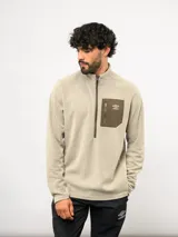 Buzo de entrenamiento Umbro con medio cierre frontal, cuello alto y bolsillo en el pecho de nylon con cierre. Presenta una textura sutil en el tejido y logo de la marca estampado en el bolsillo.
